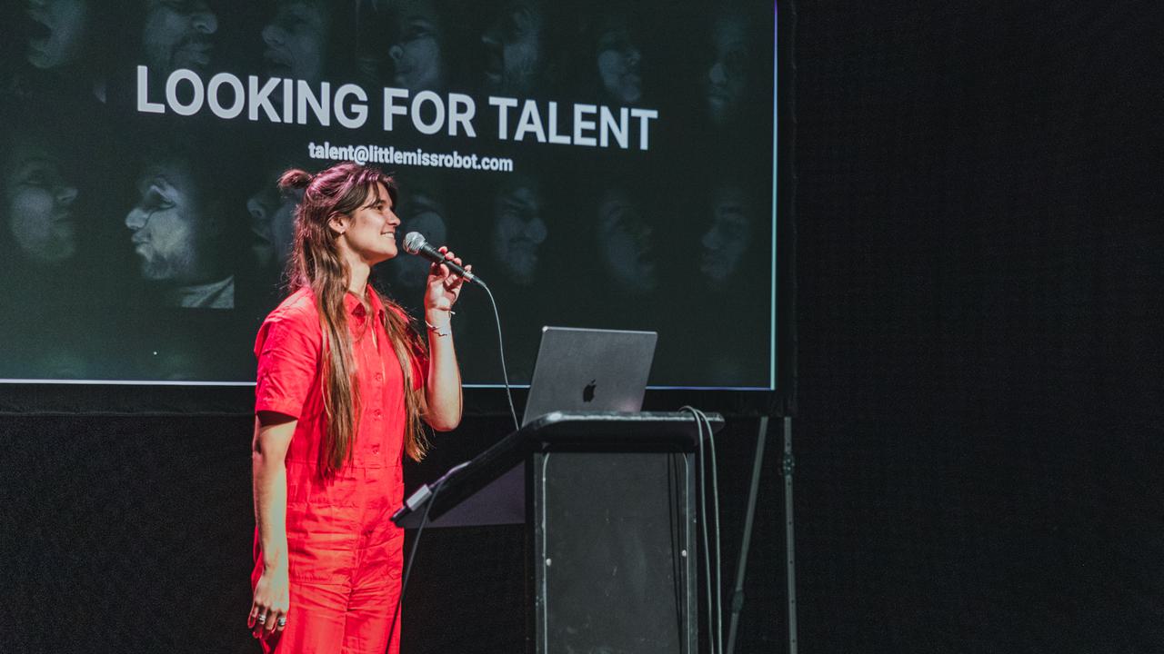 Person in a red trouser suit presenting on a stage
